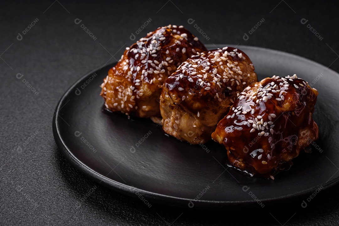 Delicioso frango frito suculento com molho teriyaki agridoce e sementes de gergelim em um fundo escuro de concreto