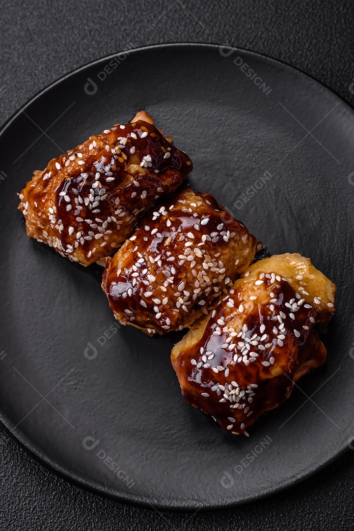 Delicioso frango frito suculento com molho teriyaki agridoce e sementes de gergelim em um fundo escuro de concreto