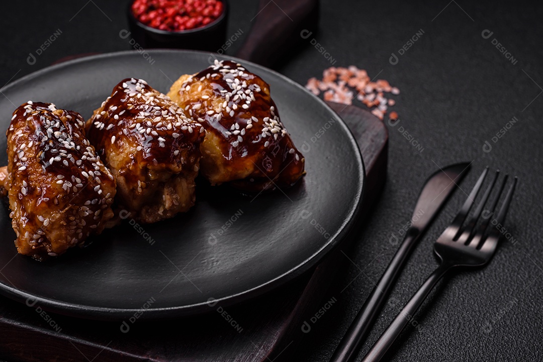 Delicioso frango frito suculento com molho teriyaki agridoce e sementes de gergelim em um fundo escuro de concreto