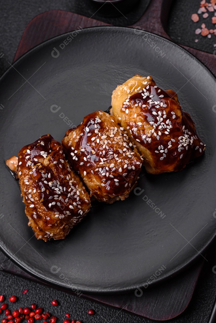 Delicioso frango frito suculento com molho teriyaki agridoce e sementes de gergelim em um fundo escuro de concreto