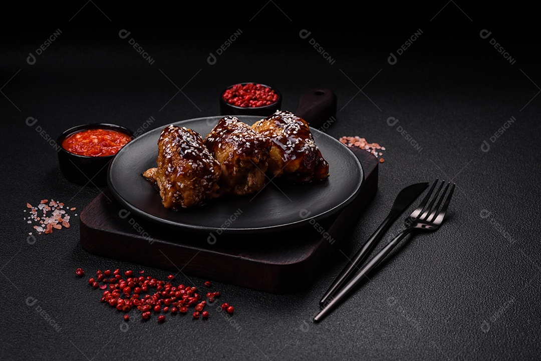 Delicioso frango frito suculento com molho teriyaki agridoce e sementes de gergelim em um fundo escuro de concreto