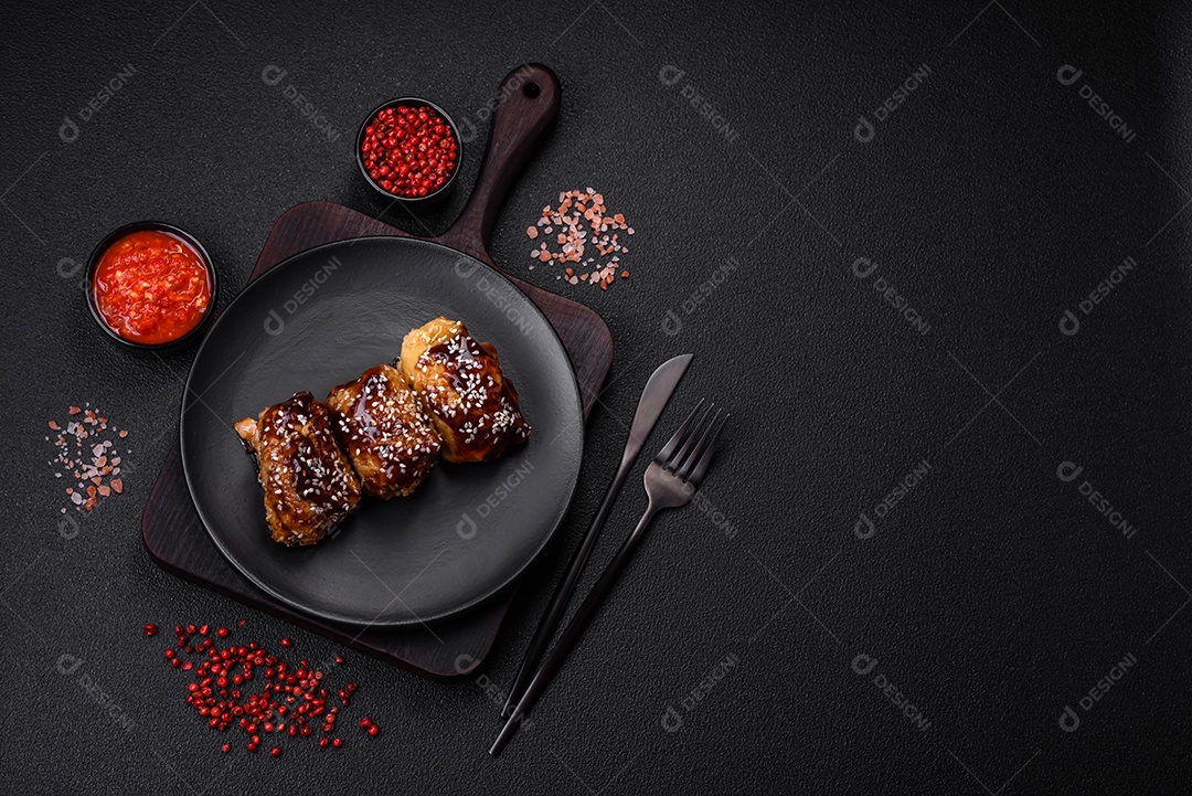 Delicioso frango frito suculento com molho teriyaki agridoce e sementes de gergelim em um fundo escuro de concreto