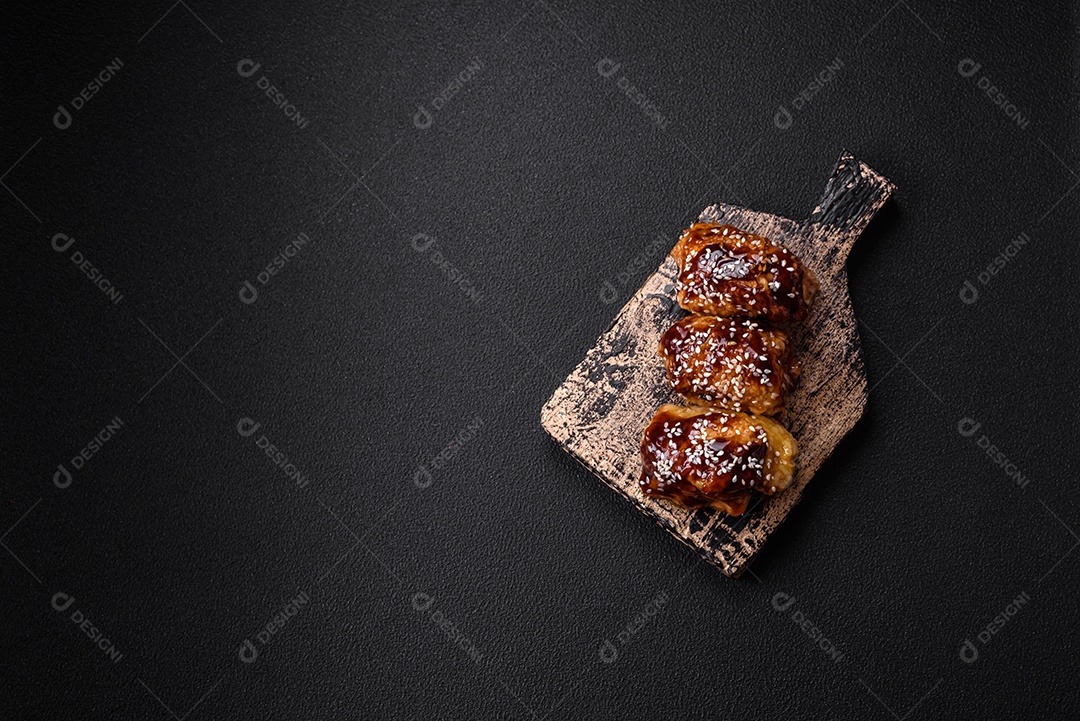 Delicioso frango frito suculento com molho teriyaki agridoce e sementes de gergelim em um fundo escuro de concreto