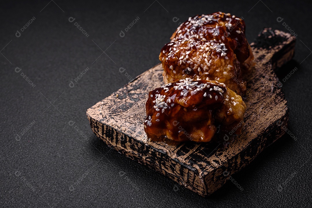 Delicioso frango frito suculento com molho teriyaki agridoce e sementes de gergelim em um fundo escuro de concreto