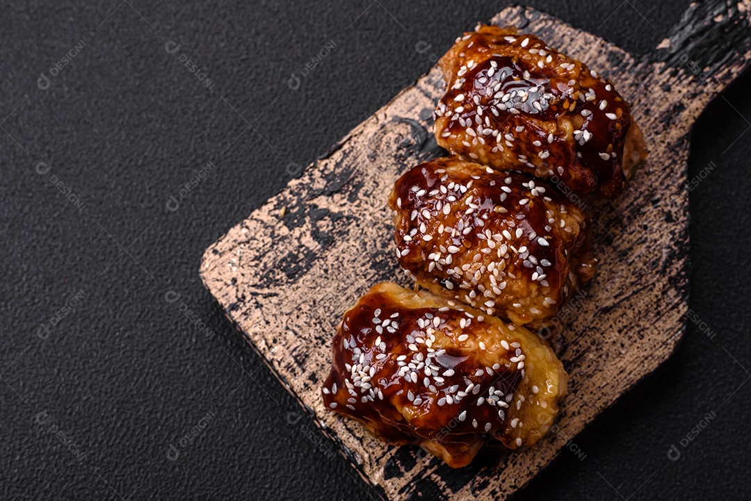 Delicioso frango frito suculento com molho teriyaki agridoce e sementes de gergelim em um fundo escuro de concreto