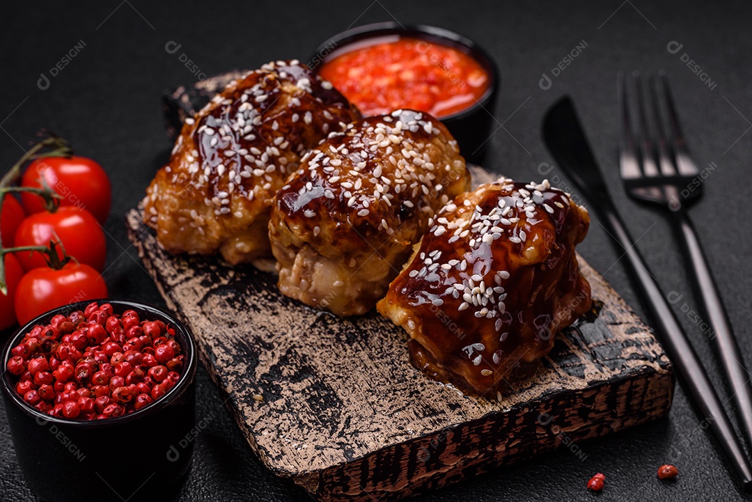 Delicioso frango frito suculento com molho teriyaki agridoce e sementes de gergelim em um fundo escuro de concreto