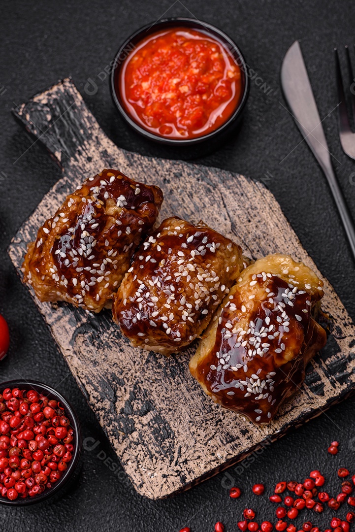 Delicioso frango frito suculento com molho teriyaki agridoce e sementes de gergelim em um fundo escuro de concreto