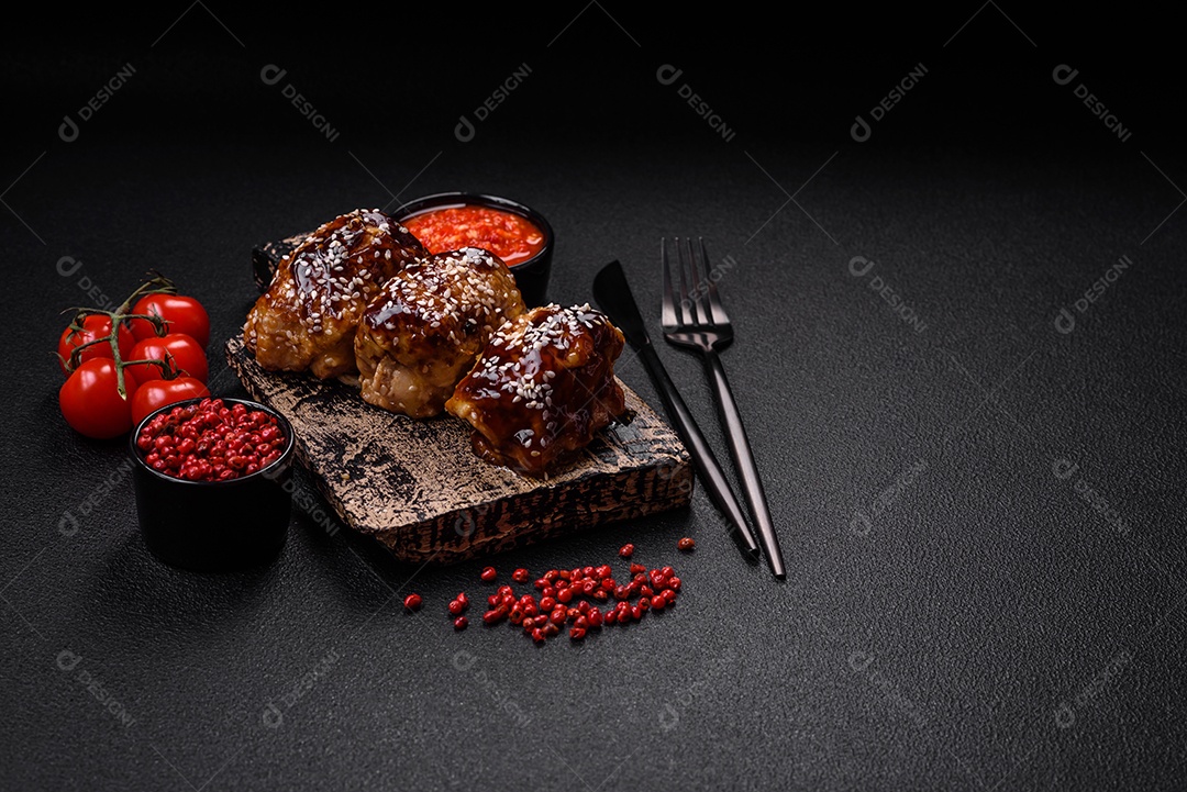 Delicioso frango frito suculento com molho teriyaki agridoce e sementes de gergelim em um fundo escuro de concreto