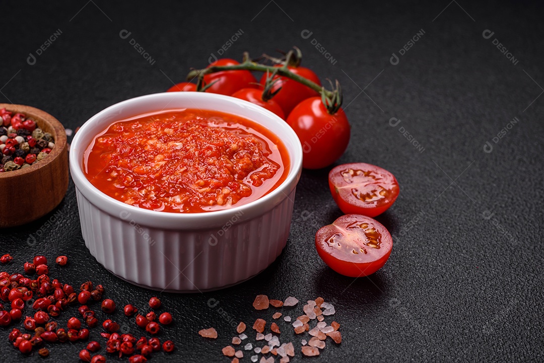 Delicioso molho vermelho picante com sal e especiarias em uma tigela de cerâmica sobre um fundo escuro de concreto