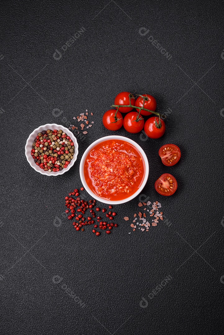 Delicioso molho vermelho picante com sal e especiarias em uma tigela de cerâmica sobre um fundo escuro de concreto
