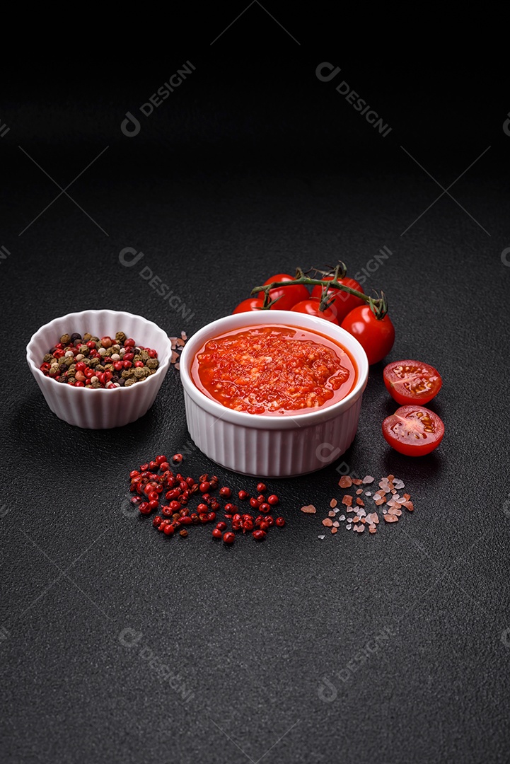 Delicioso molho vermelho picante com sal e especiarias em uma tigela de cerâmica sobre um fundo escuro de concreto