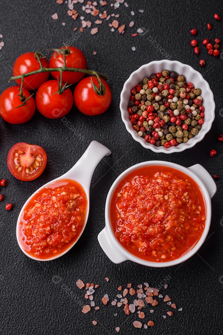 Delicioso molho vermelho picante com sal e especiarias em uma tigela de cerâmica sobre um fundo escuro de concreto