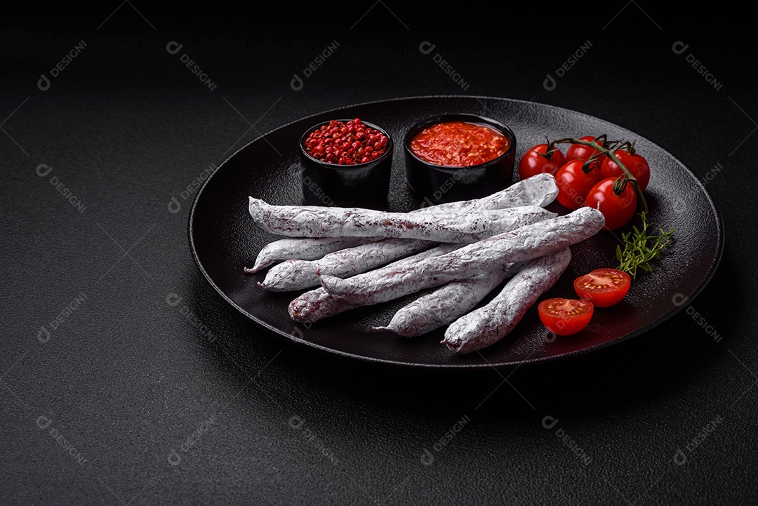 Delicioso fuet de linguiça defumada espanhola com sal e especiarias sobre um fundo escuro de concreto