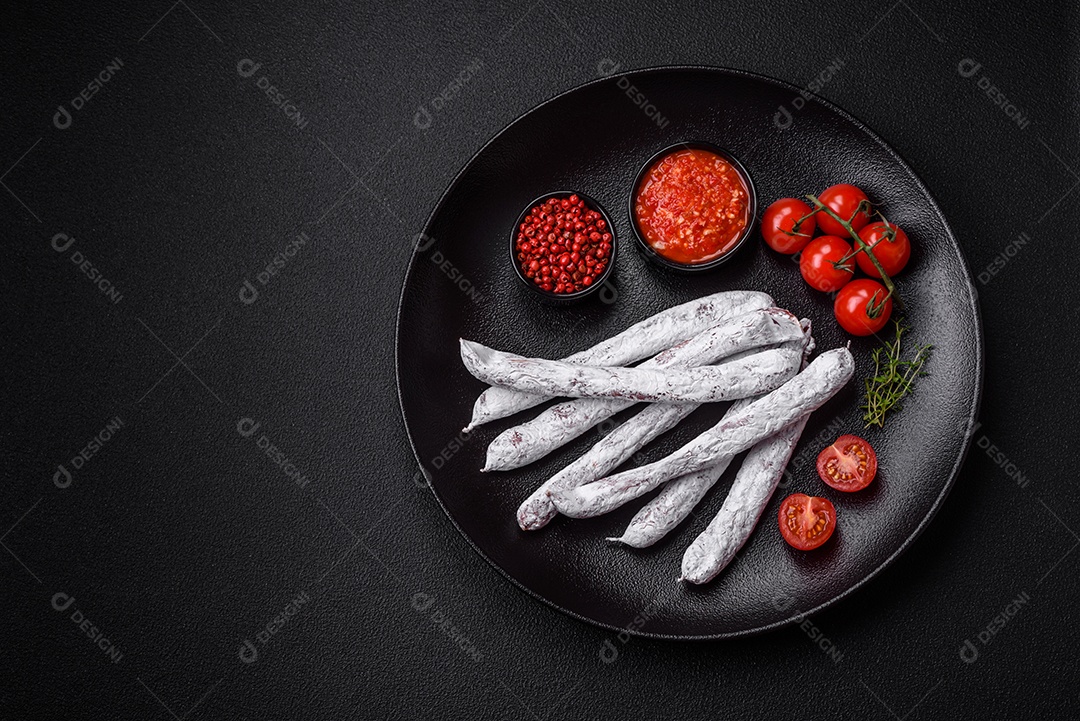 Delicioso fuet de linguiça defumada espanhola com sal e especiarias sobre um fundo escuro de concreto