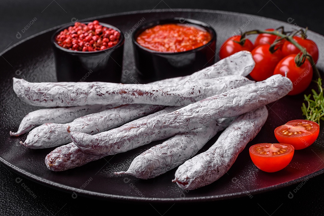 Delicioso fuet de linguiça defumada espanhola com sal e especiarias sobre um fundo escuro de concreto