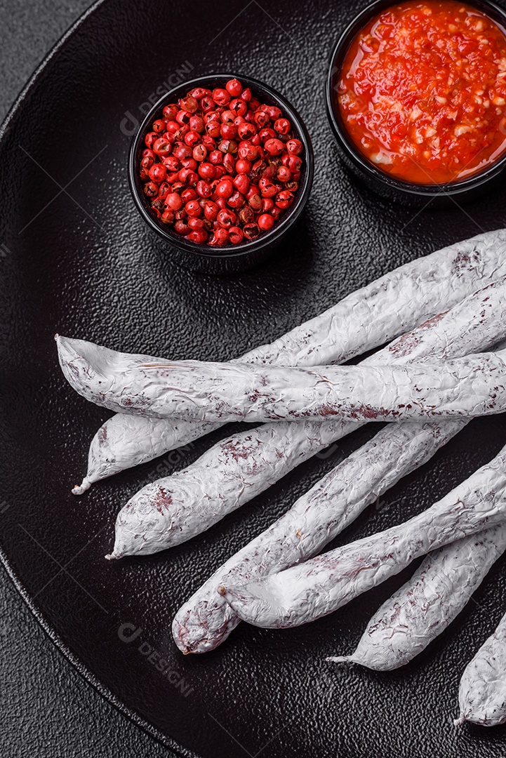 Delicioso fuet de linguiça defumada espanhola com sal e especiarias sobre um fundo escuro de concreto