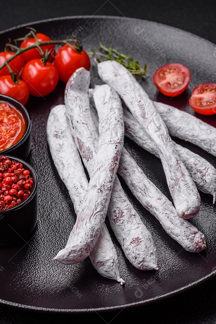 Delicioso fuet de linguiça defumada espanhola com sal e especiarias sobre um fundo escuro de concreto