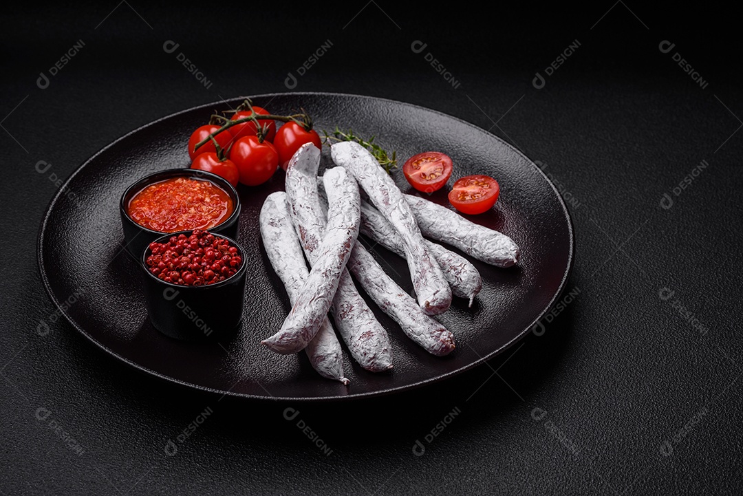 Delicioso fuet de linguiça defumada espanhola com sal e especiarias sobre um fundo escuro de concreto