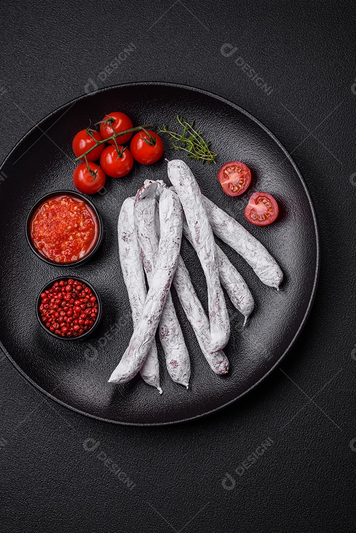 Delicioso fuet de linguiça defumada espanhola com sal e especiarias sobre um fundo escuro de concreto
