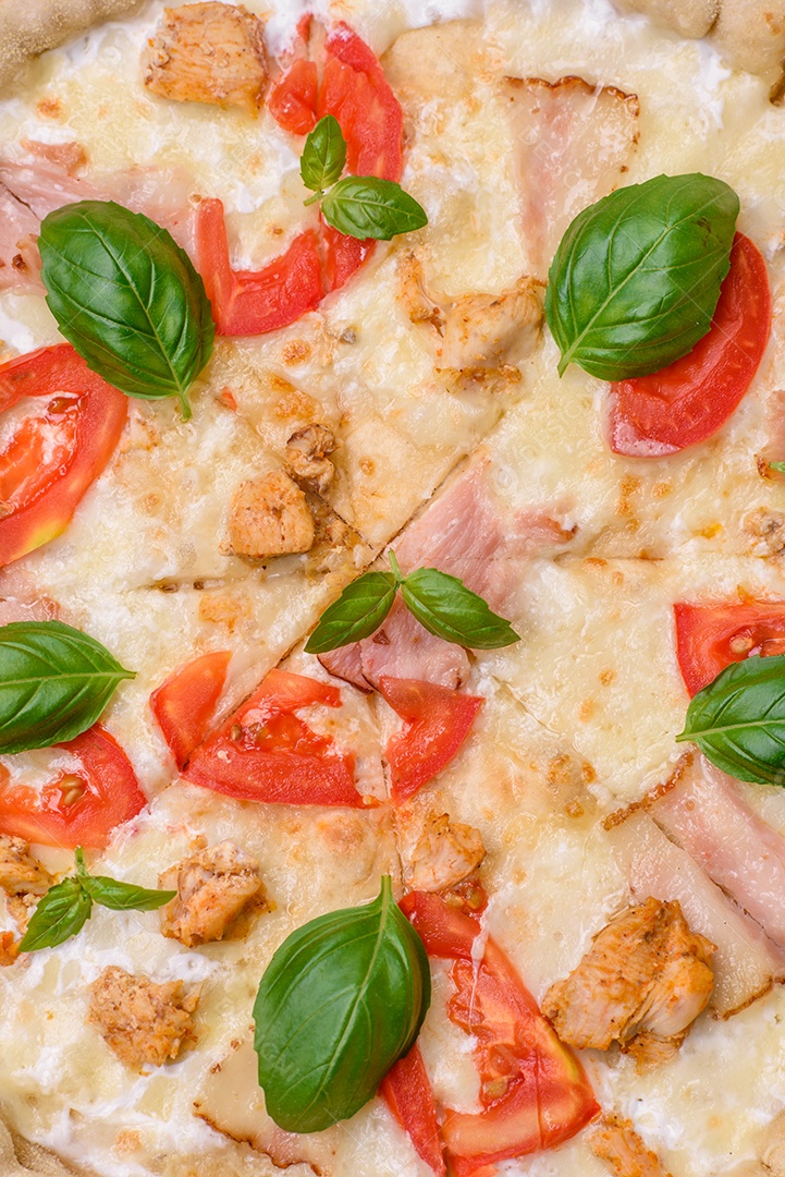 Deliciosa pizza quente com frango, tomate, queijo e bacon, com sal e especiarias e sobre fundo escuro de concreto