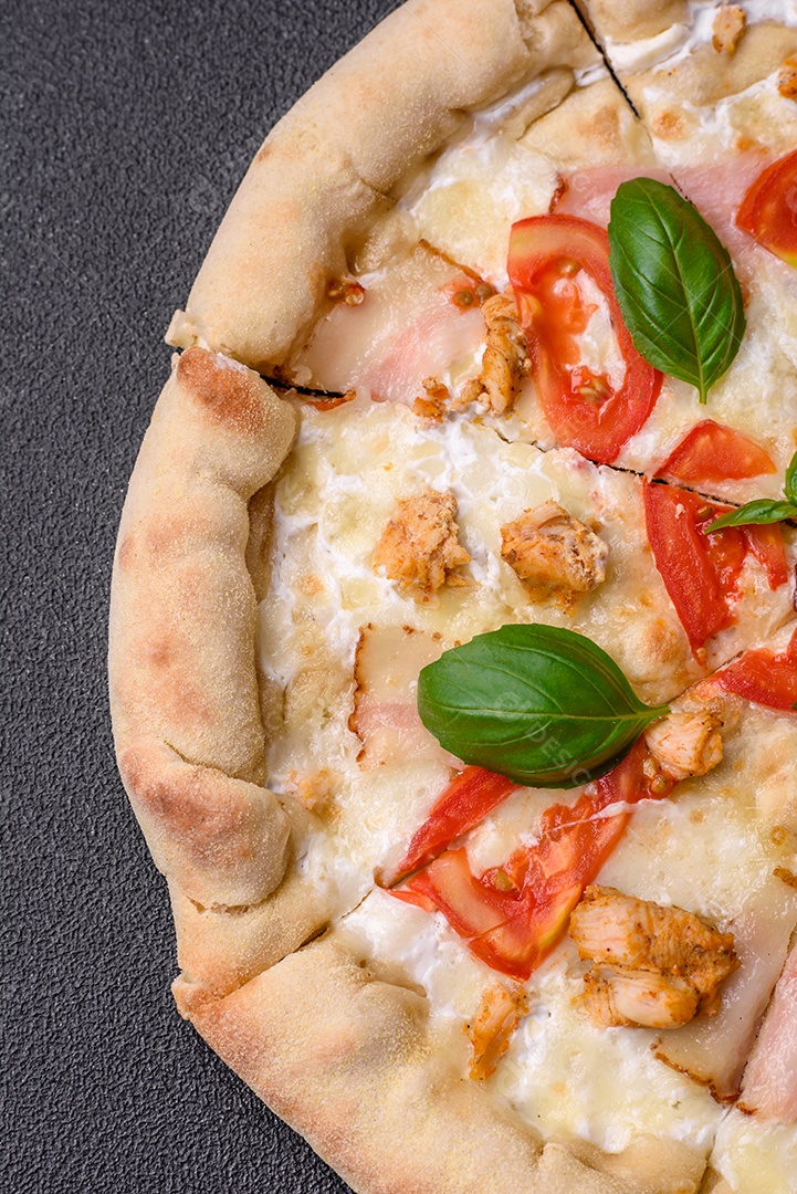 Deliciosa pizza quente com frango, tomate, queijo e bacon, com sal e especiarias e sobre fundo escuro de concreto