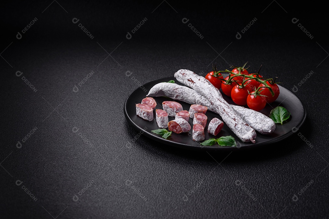 Delicioso fuet de linguiça defumada espanhola com sal e especiarias sobre um fundo escuro de concreto