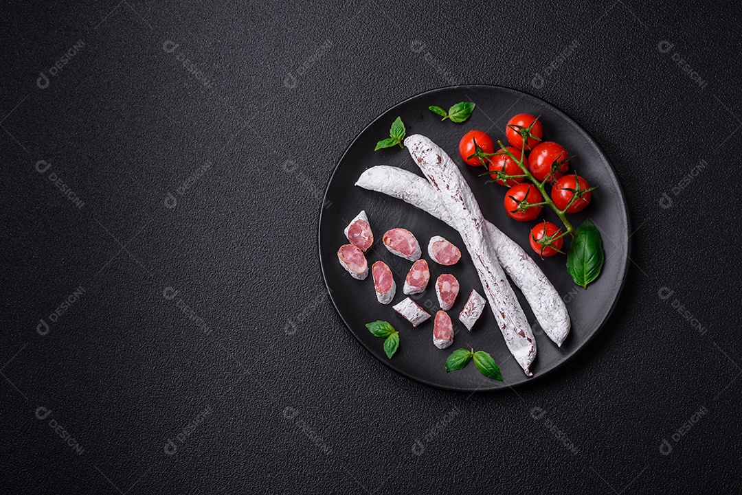 Delicioso fuet de linguiça defumada espanhola com sal e especiarias sobre um fundo escuro de concreto