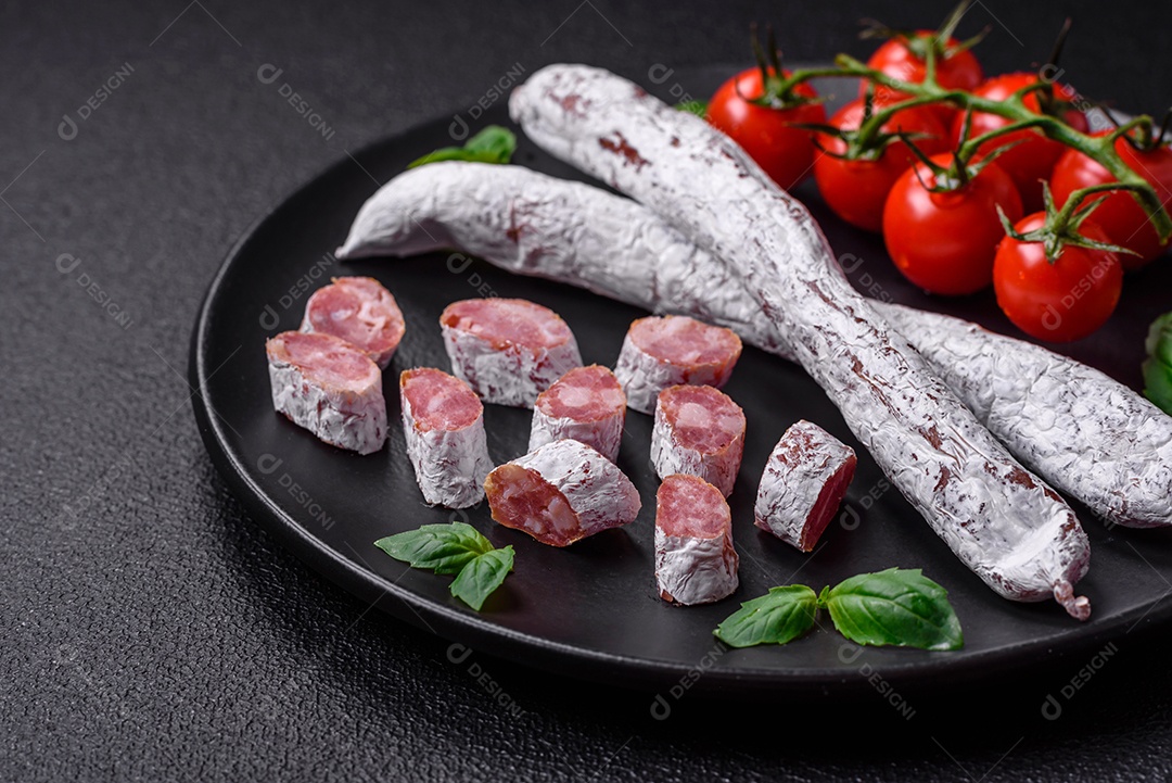 Delicioso fuet de linguiça defumada espanhola com sal e especiarias sobre um fundo escuro de concreto