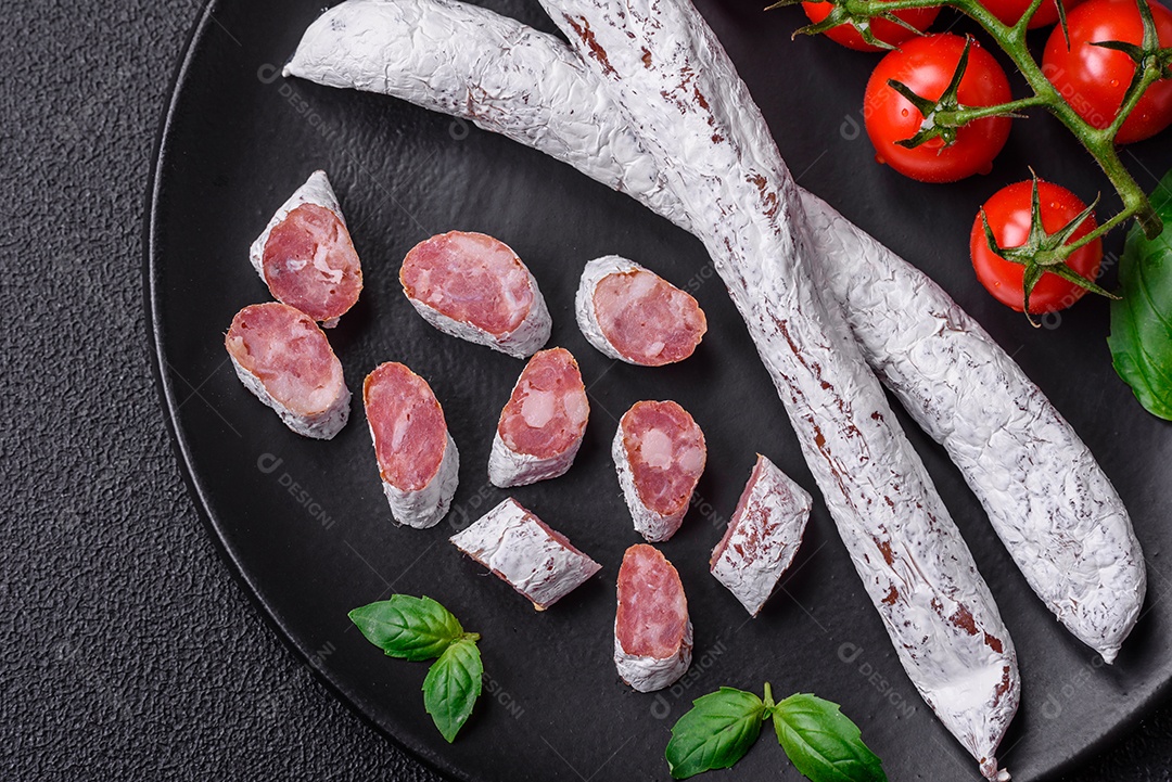 Delicioso fuet de linguiça defumada espanhola com sal e especiarias sobre um fundo escuro de concreto