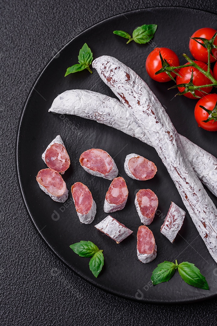 Delicioso fuet de linguiça defumada espanhola com sal e especiarias sobre um fundo escuro de concreto