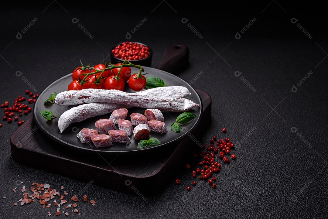 Delicioso fuet de linguiça defumada espanhola com sal e especiarias sobre um fundo escuro de concreto