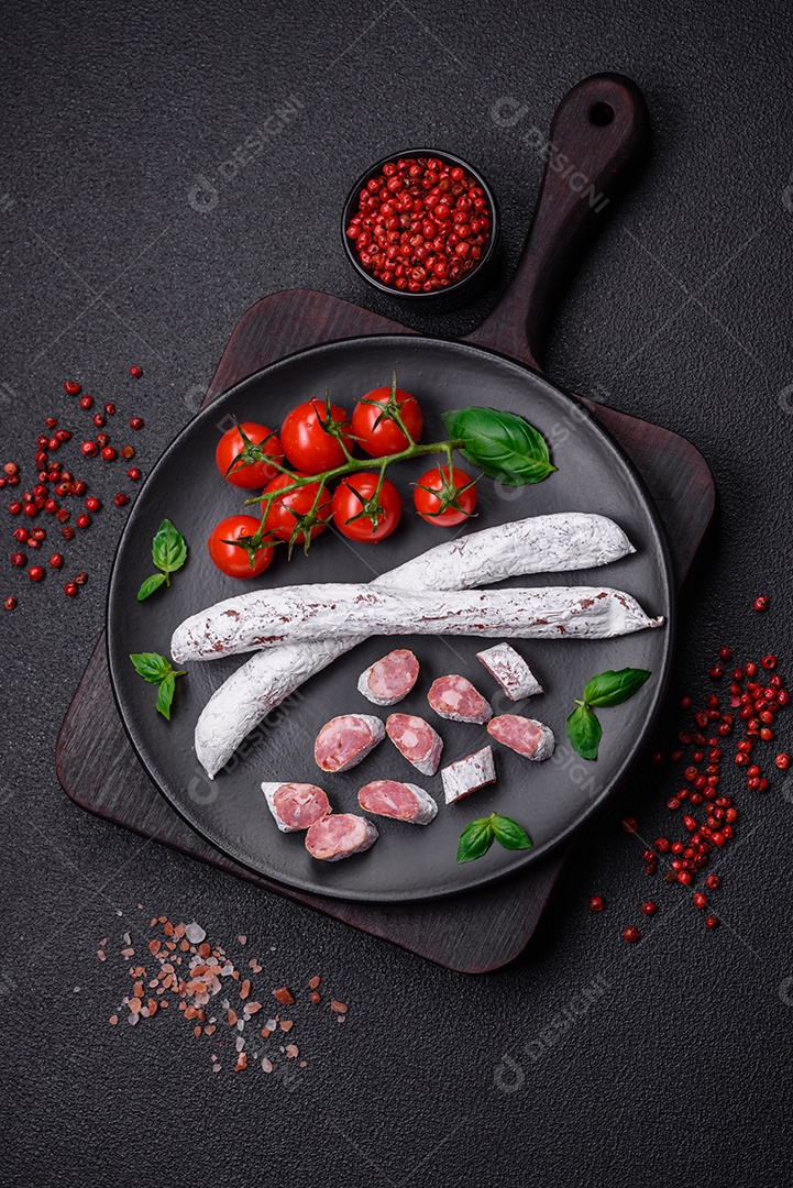 Delicioso fuet de linguiça defumada espanhola com sal e especiarias sobre um fundo escuro de concreto