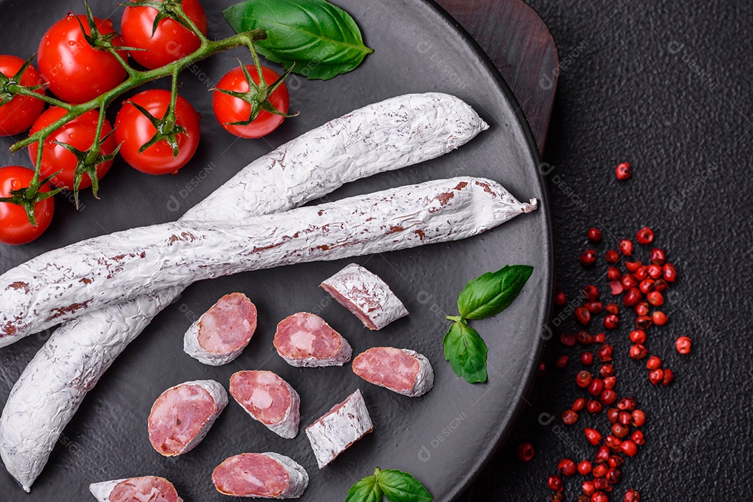 Delicioso fuet de linguiça defumada espanhola com sal e especiarias sobre um fundo escuro de concreto
