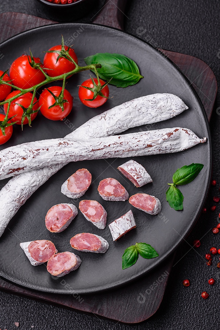 Delicioso fuet de linguiça defumada espanhola com sal e especiarias sobre um fundo escuro de concreto