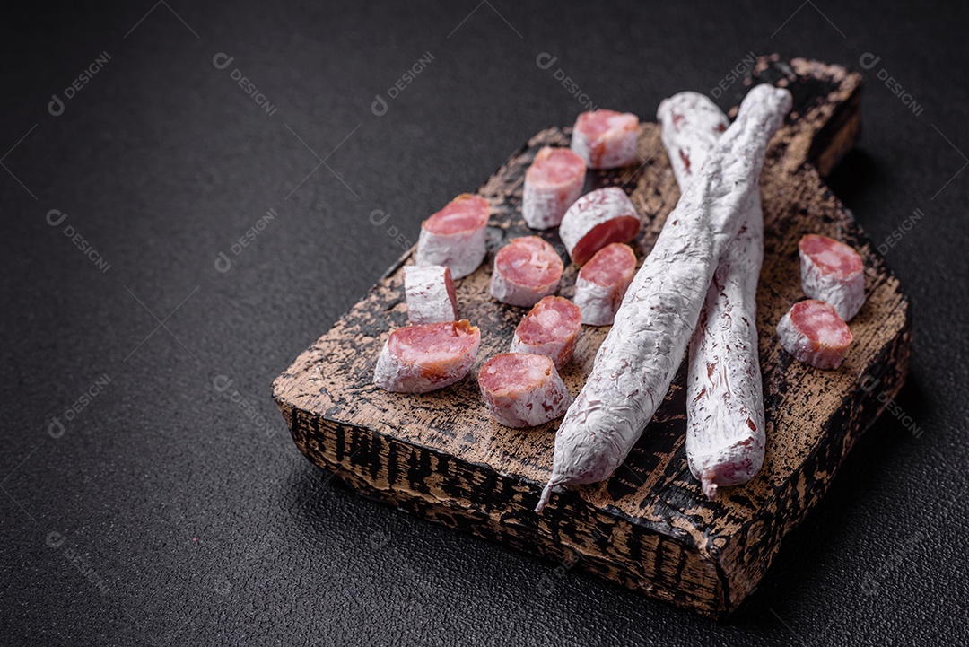 Delicioso fuet de linguiça defumada espanhola com sal e especiarias sobre um fundo escuro de concreto