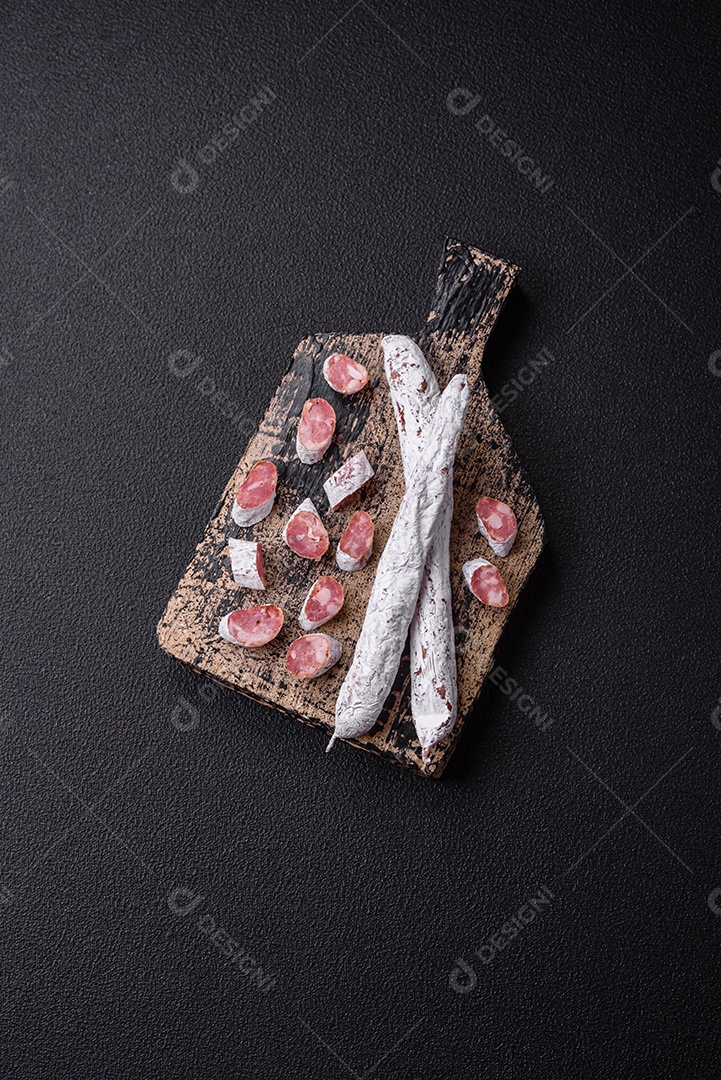 Delicioso fuet de linguiça defumada espanhola com sal e especiarias sobre um fundo escuro de concreto