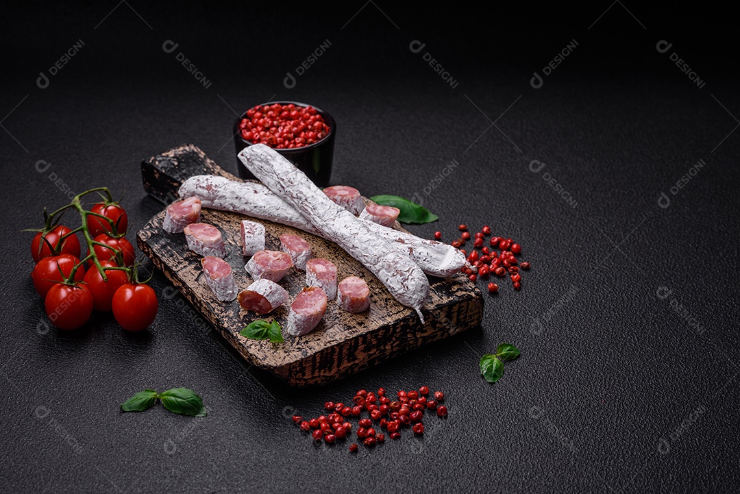 Delicioso fuet de linguiça defumada espanhola com sal e especiarias sobre um fundo escuro de concreto