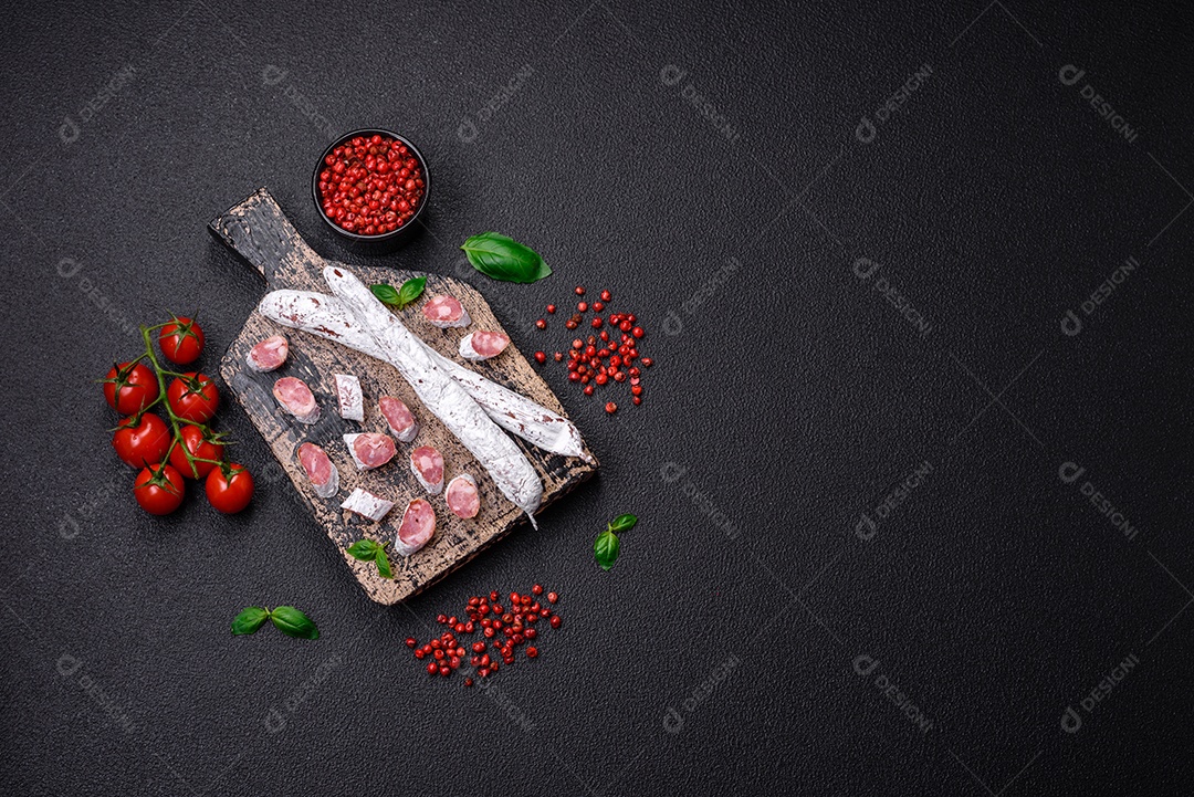 Delicioso fuet de linguiça defumada espanhola com sal e especiarias sobre um fundo escuro de concreto