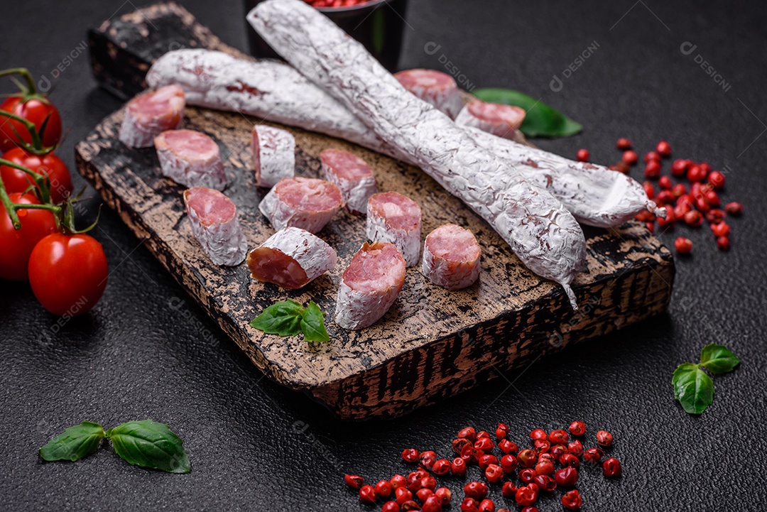 Delicioso fuet de linguiça defumada espanhola com sal e especiarias sobre um fundo escuro de concreto