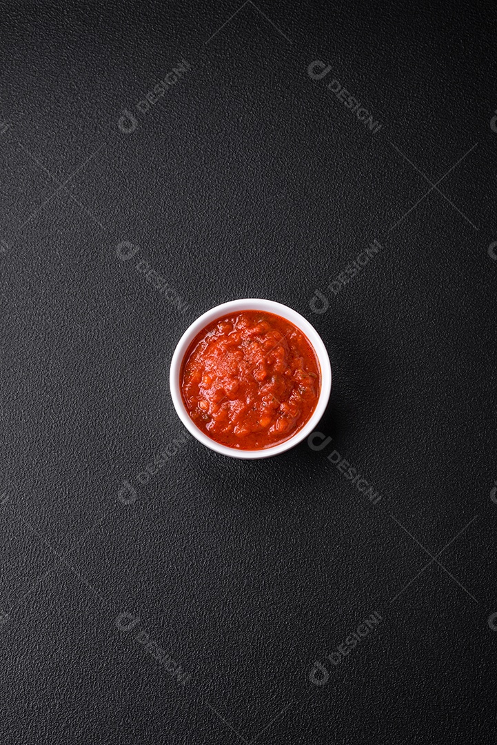 Delicioso molho Napoletana vermelho com cebola, sal, especiarias e ervas em uma tigela branca sobre fundo escuro de concreto