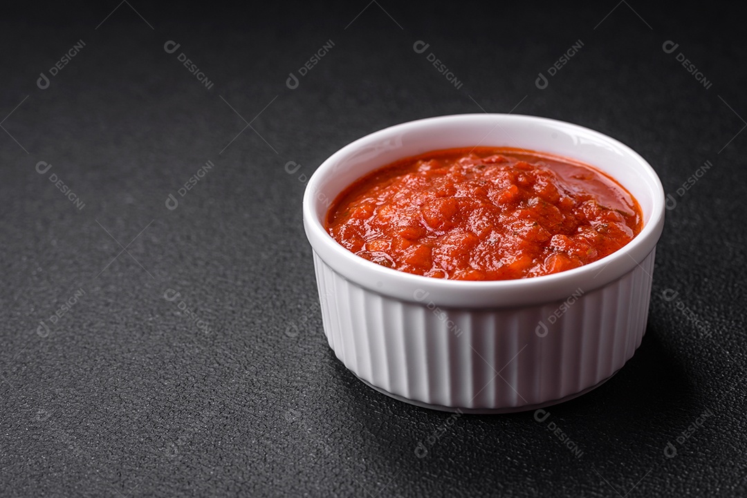 Delicioso molho Napoletana vermelho com cebola, sal, especiarias e ervas em uma tigela branca sobre fundo escuro de concreto