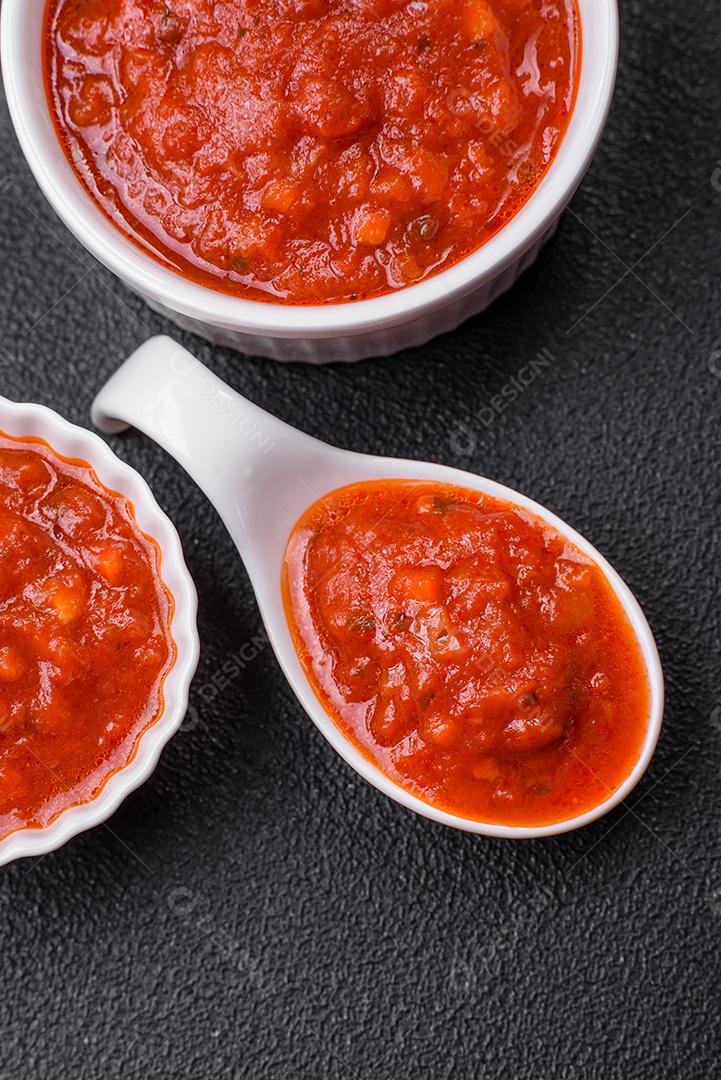 Delicioso molho Napoletana vermelho com cebola, sal, especiarias e ervas em uma tigela branca sobre fundo escuro de concreto