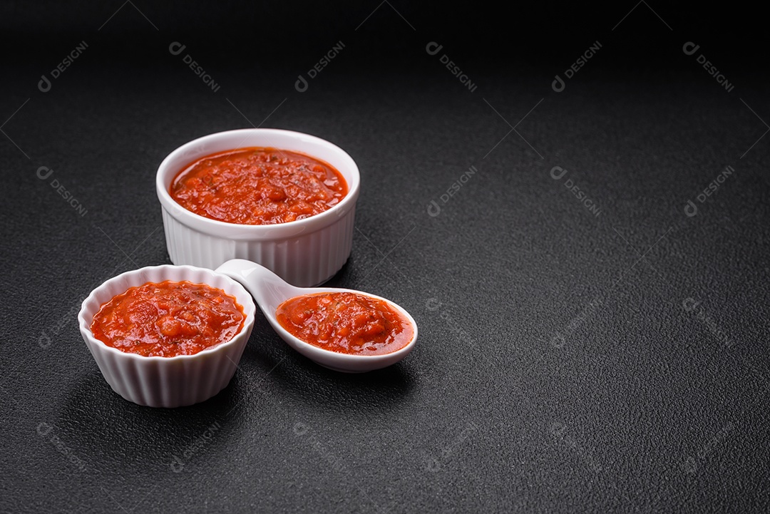 Delicioso molho Napoletana vermelho com cebola, sal, especiarias e ervas em uma tigela branca sobre fundo escuro de concreto