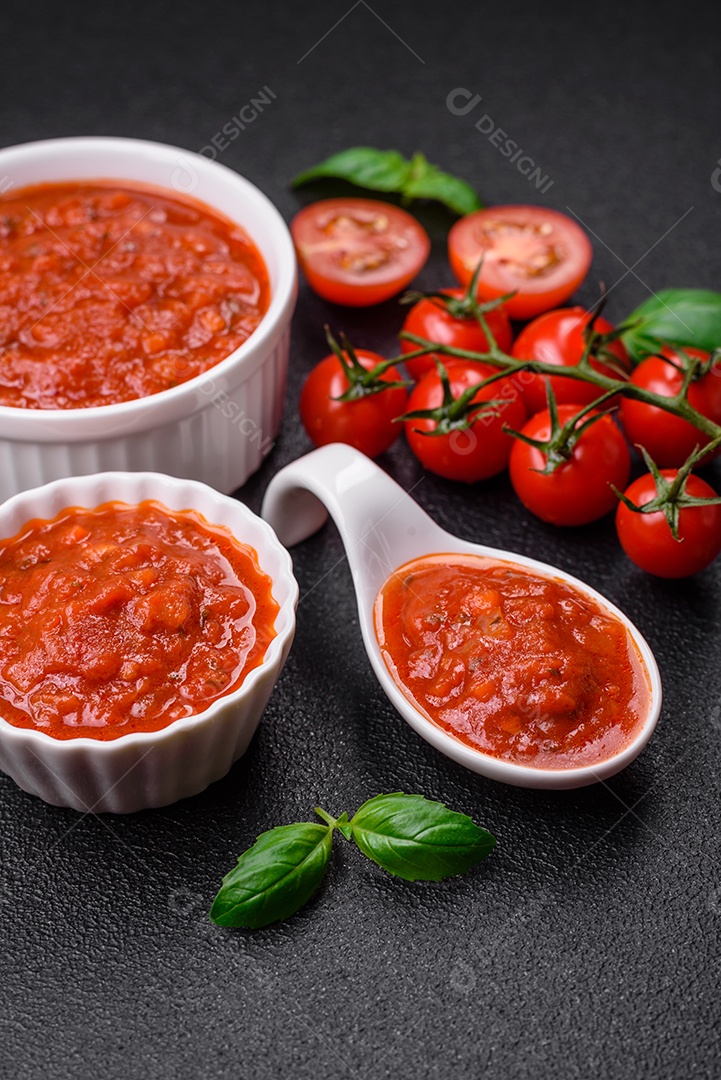 Delicioso molho Napoletana vermelho com cebola, sal, especiarias e ervas em uma tigela branca sobre fundo escuro de concreto