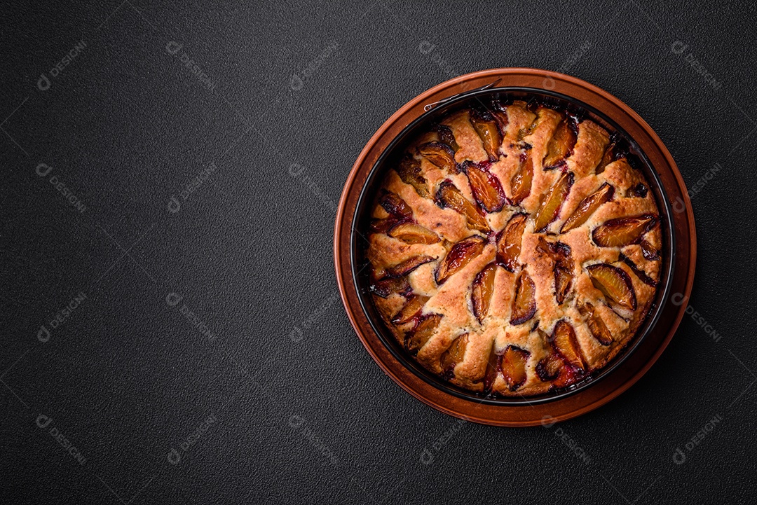 Deliciosa torta caseira aromática doce com ameixas maduras sobre um fundo escuro de concreto