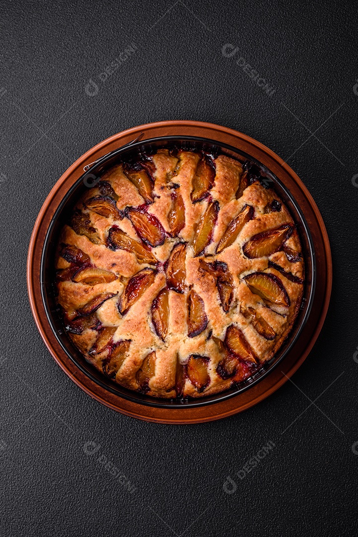 Deliciosa torta caseira aromática doce com ameixas maduras sobre um fundo escuro de concreto