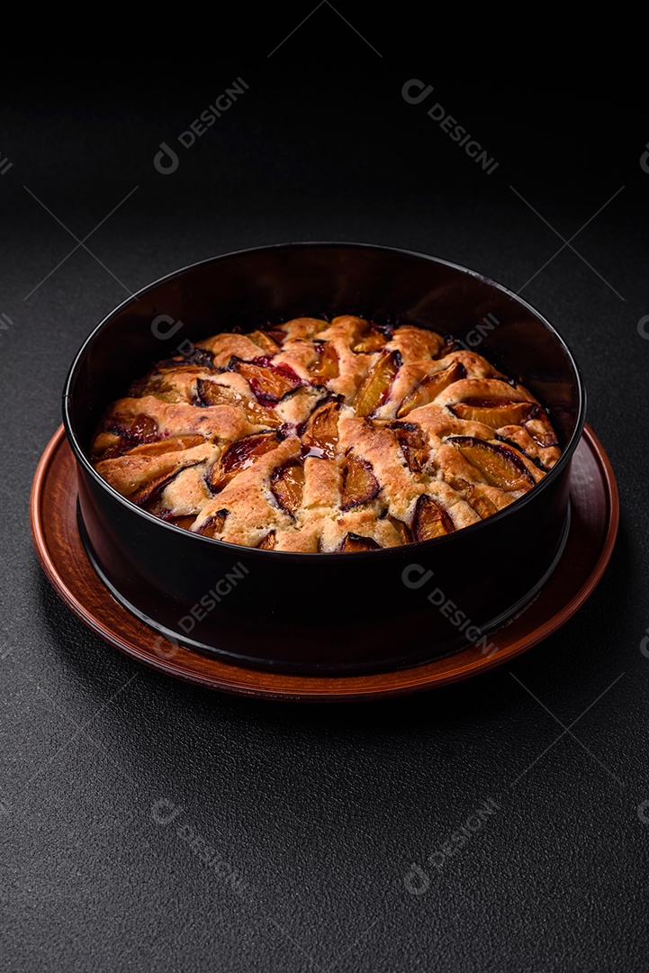 Deliciosa torta caseira aromática doce com ameixas maduras sobre um fundo escuro de concreto