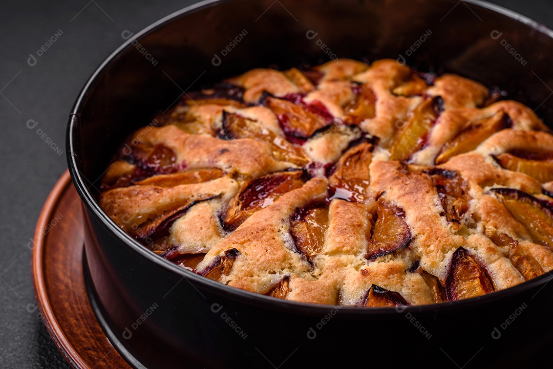 Deliciosa torta caseira aromática doce com ameixas maduras sobre um fundo escuro de concreto