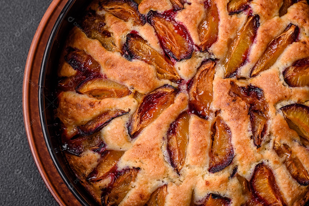 Deliciosa torta caseira aromática doce com ameixas maduras sobre um fundo escuro de concreto