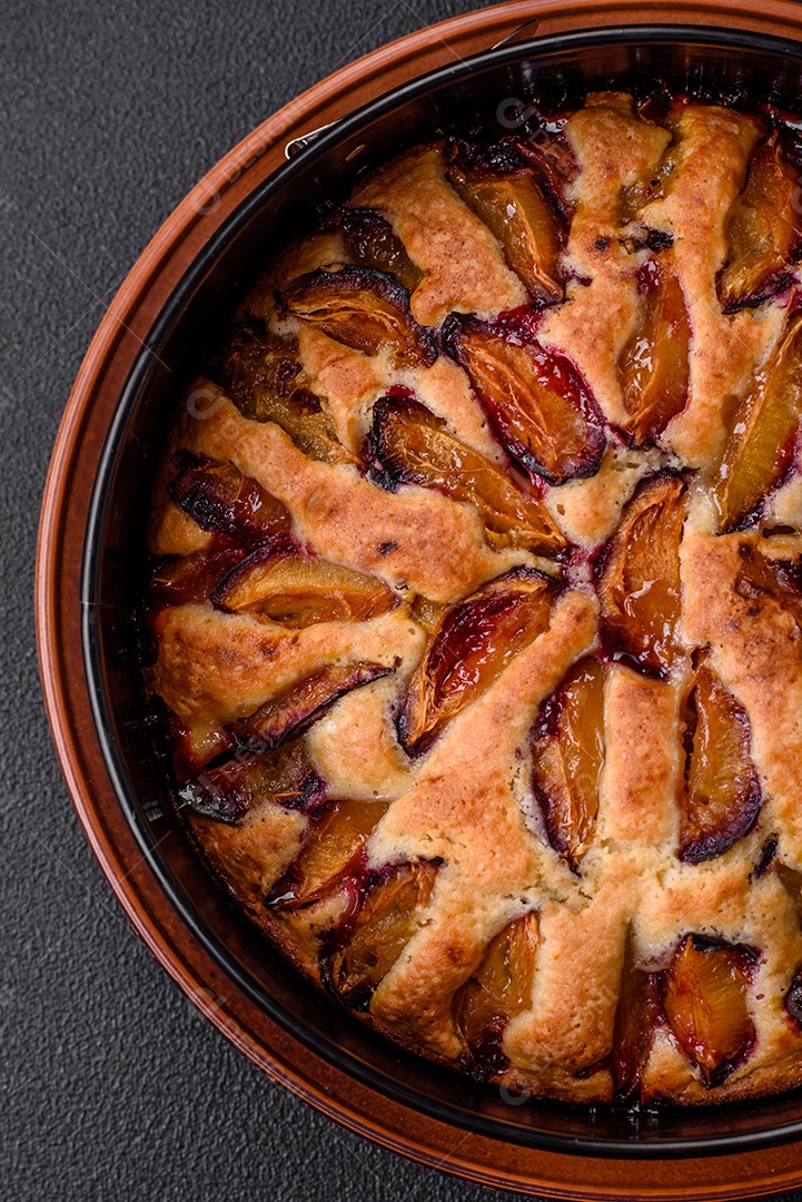 Deliciosa torta caseira aromática doce com ameixas maduras sobre um fundo escuro de concreto